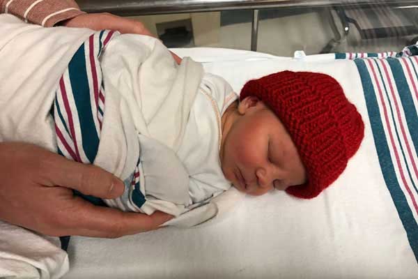 a sleeping newborn wearing a red knit hat